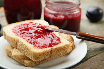 Bread with plum jam on grey wooden table