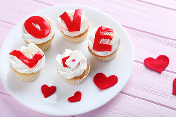 Tasty cupcakes on a pink wooden table