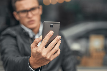 Close-up. A cute guy does selfie on a smartphone. On the street