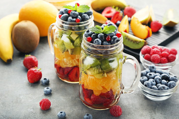 Fresh fruit salad in jars on grey wooden table