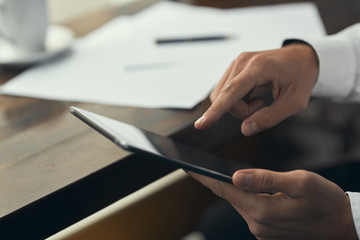 Close-up. Young man working on a tablet. A cafe. Blurred background. White shirt