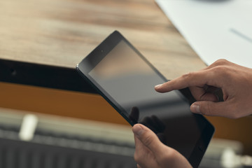 Close-up. Young man working on a tablet. A cafe. Blurred background. White shirt
