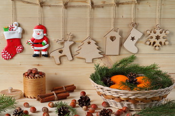 Naklejka na ściany i meble Christmas and New Year composition. Composition of Christmas and New Year decorations from plywood, a wicker basket with tangerines, nuts and fir branches on a wooden background.