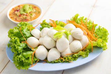 steamed fish balls with spicy dip on wooden table.