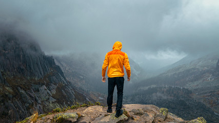 a man stands on the precipice of the mountain in the fog