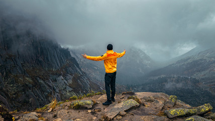 a man stands on the precipice of the mountain in the fog