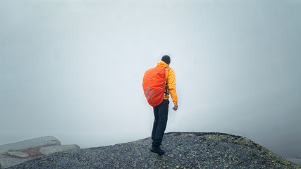 a man stands on the precipice of the mountain in the fog