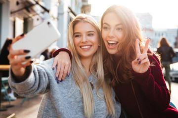 Two joyful cheerful girls taking a selfie