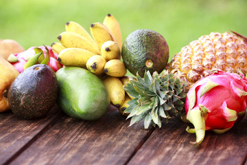 Mixed exotic fruits on wood background. Healthy eating, dieting. Top view with grass copy space