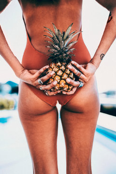 Attractive female adult holding pineapple behind her back