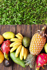 Mixed exotic fruits on wood background. Healthy eating, dieting. Top view with grass copy space