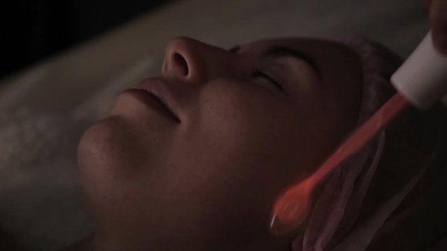 Beautiful woman has a electric darsonval massage procedure in a dark