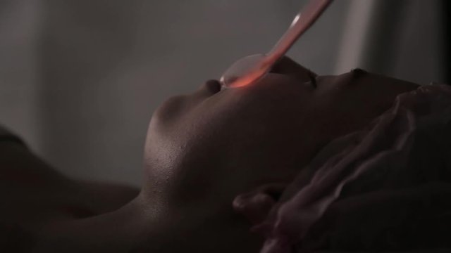 Beautiful woman has a electric darsonval massage procedure in a dark