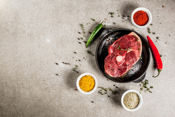 Fresh raw meat. A piece of lamb's tenderloin, with a bone, with a cutting ax, with spices for cooking on grey stone table Top view copy space