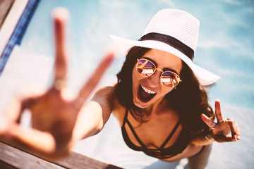 Happy young woman showing peace sign and looking at camera