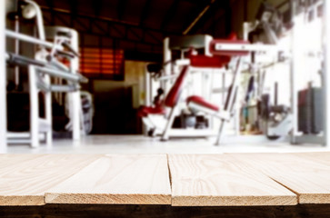 Wooden table on blurred background of fitness gym interior of modern club with equipment for your photomontage or product display.