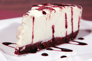 A piece of white cake with chocolate on a white plate. Picture for the menu.