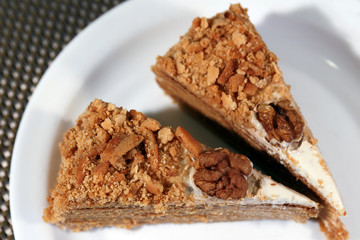 Two pieces of cake with walnuts on a white plate. View from above.