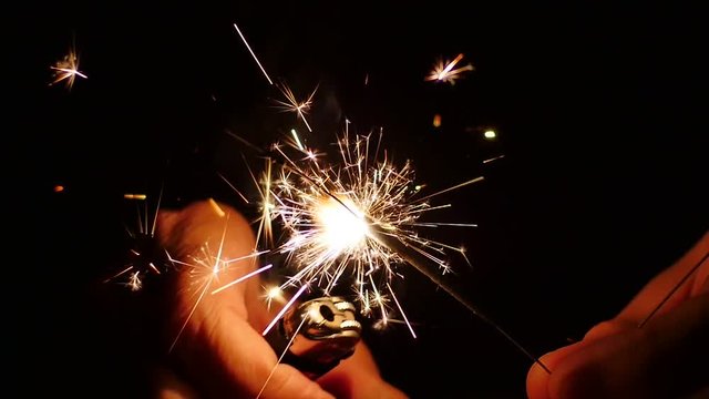 Lighting up a sparkler using a lighter in night. Close up. Best sources of flame to light an amazing bengal fire are butane lighters and propane torches. Slow Mo. Lighting Up A Sparkler With Lighter. 