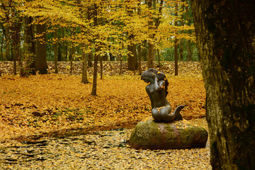A sculpture of a mermaid in the pond. Autumn landscape. Golden autumn