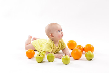 Fototapeta na wymiar cute smiling healthy child lies on a white background among fruit
