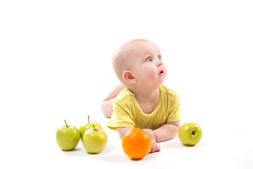 Fototapeta na wymiar cute smiling baby lying on his stomach among fruits and looking at the camera