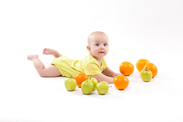 cute smiling healthy child lies on a white background among fruit