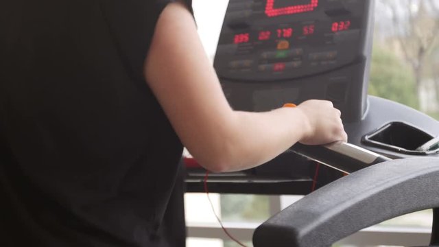 woman pushing buttons on treadmill panel, workout in gym