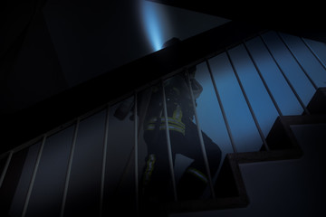 Feuerwehrmann in dunklem Treppenhaus mit Taschenlampe
