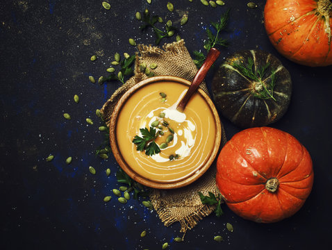 Creamy pumpkin soup in a wooden bowl, top view