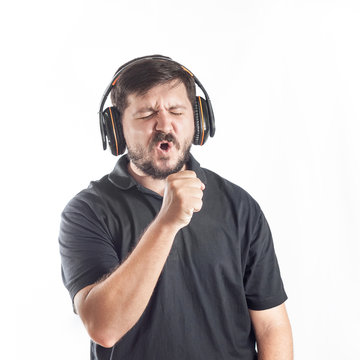 Portrait of 30 years old caucasian man sing into imagine microphone and listen music from headphones