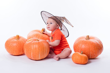 Baby in orange t-shirt on a white background sitting in a witche