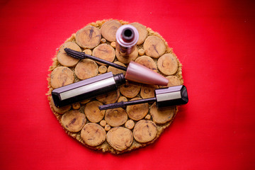 Two of various mascara brushes with mascara strokes on red and wooden background. Closeup Mascara Bottle and Brush. Mascara on a red Background, New Form Brush. Mascara New formula 