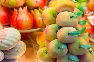 Marzipan assortment. Sweet marzipan with colorful fruit shapes, in the window of a sweet shop. Cakes with marzipan in the form of peach. Marzipan with fruit shape.