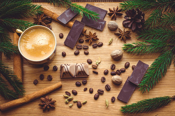 Hot coffee and christmas decorations . Cup of coffee and chocolate on wooden table. Christmas decorations on a kitchen, gifts and food on a wooden background. Magic moments in everyday life