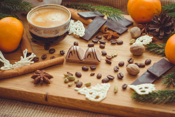 Hot coffee and christmas decorations . Cup of coffee and chocolate on wooden table. Christmas decorations on a kitchen, gifts and food on a wooden background. Magic moments in everyday life