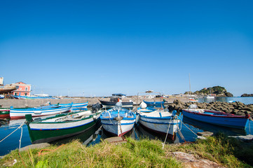 Fototapeta na wymiar Sicilian landscape: fisher boats with the Islands of the Cyclops on the background