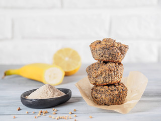 Healthy gluten-free homemmade banana muffins with buckwheat flour. Stack of three vegan muffins with poppy seeds and lemon on gray wooden table. Copy space