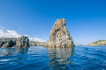 Fototapeta premium Sicilian landscape: fisher boat with the Islands of the Cyclops on the background