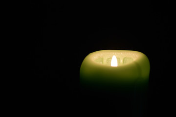 Flame burning green candle in the dark close up