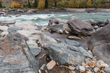 huge rocks on the shore of the turquoise river