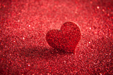 Fototapeta premium Valentines bright red heart on a red glitter background.