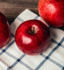 Autumn composition with fresh red apples in a wooden basket on rustic wooden background. Red apples on rustic kitchen towel