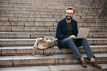 Portrait of young smiling man using laptop computer