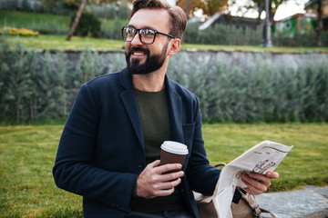 Fototapeta premium Portrait of a smiling young man sitting with a newspaper