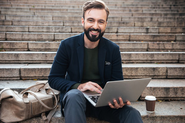 Portrait of a smiling attractive man working on laptop