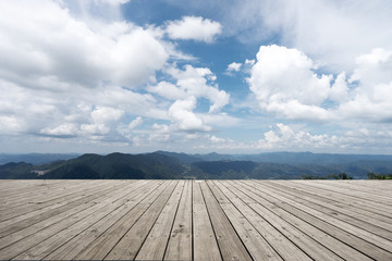 empty wooden floor with green hill in cloud sky