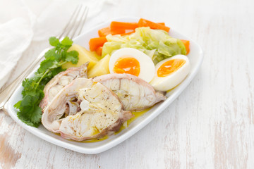boiled fish with boiled vegetables on white plate