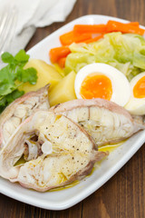 boiled fish with boiled potato, carrot, cabbage and egg on white plate