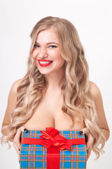 naked to the waist beautiful blonde with big breasts standing on a white background and holding a gift and smiling at the camera, selective focus on the tablet